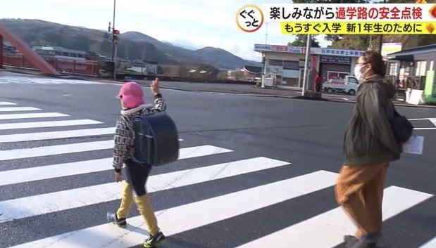 手をあげて横断歩道を渡る淺川君