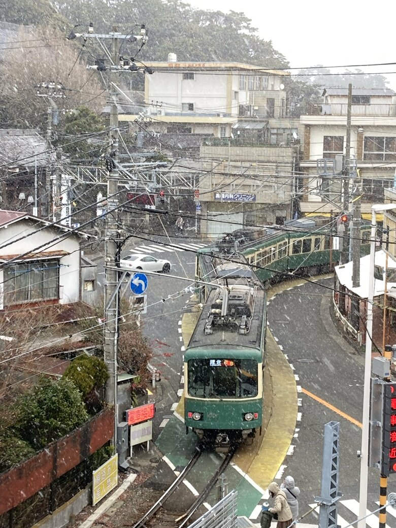 雪の降る中、路面を走る江ノ電
