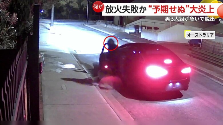 住宅に液体をまく黒ずくめの男たち