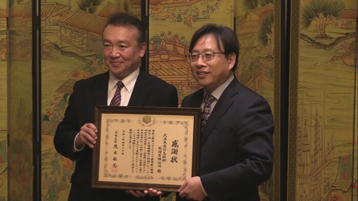 バス手配に尽力した朱敦尭さん(右) 後に日本大使館から感謝状を贈られた