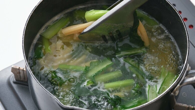 途中で小松菜の茎、葉を入れる（『史上最高！おうちイタリアン』（講談社）から抜粋）
