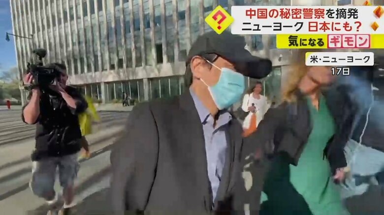 弁護士に腕を引かれて歩く男。後ろにはカメラが追いかけている
