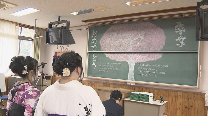 3年3組の教室の黒板アートを見る卒業生