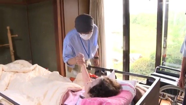 訪問診療を終え、患者の手を握る