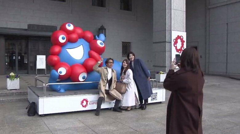 ミャクミャク像の前で記念撮影する人たち