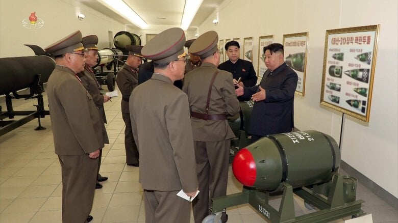 北朝鮮は一昨年、火山31"核弾頭"を超大型放射砲や火星11カ ミサイルに搭載することを示唆(後ろのポスター)