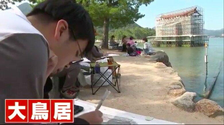 小刻みにペンを動かし、複雑な大鳥居をデッサンする男性