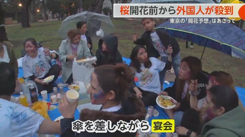 傘を差しながら宴会を続けるネパール人のグループ