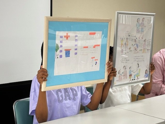 絵画を掲げるアフリカ国籍の姉妹