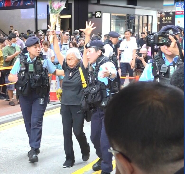 花束を掲げ警察に連行される女性（6月4日）