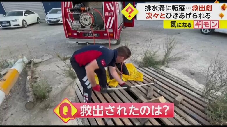 消防隊員が、排水溝に工具を差し込んでいる