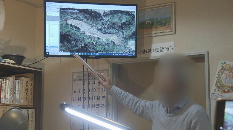 画像を指しながら崩落の原因について自らの考えを説明する前土地所有者