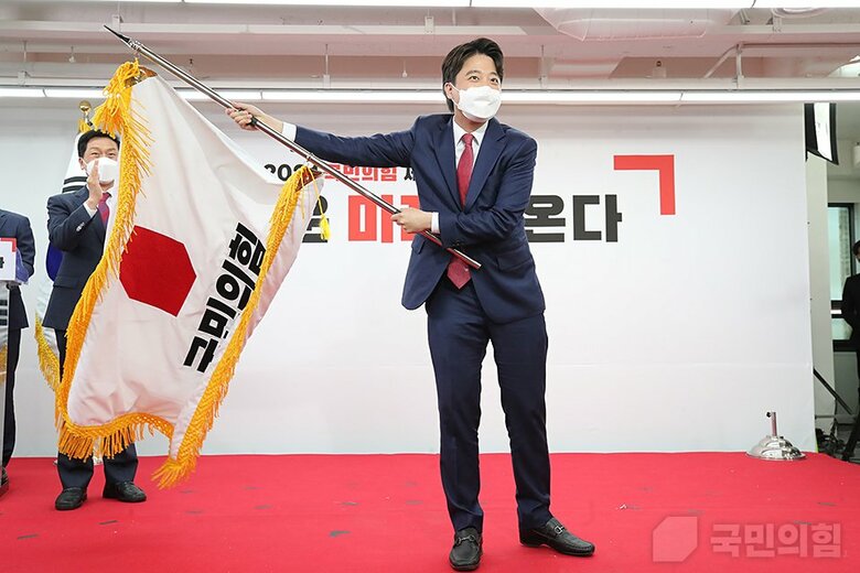 党旗を掲げる李新代表（「国民の力」HPより）