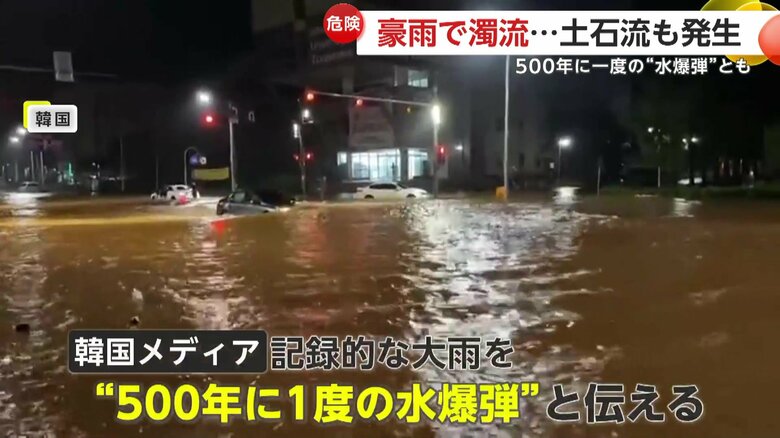 “500年に一度の水爆弾”と伝えられる豪雨の中、浸水した道路を進む車
