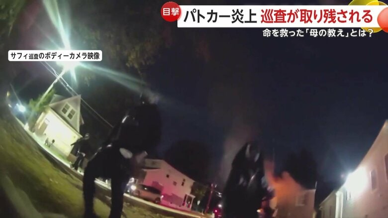 炎上するパトカーから巡査を引きずり出す2人
