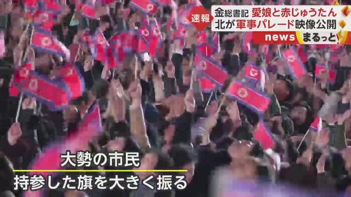 夜空に舞う国旗を見て大勢の市民が持参した旗を振っている
