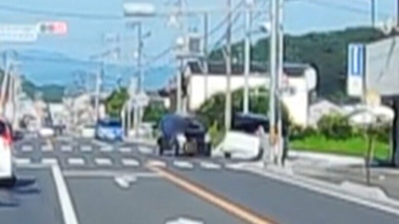 接触した衝撃でバランスを崩す白い車