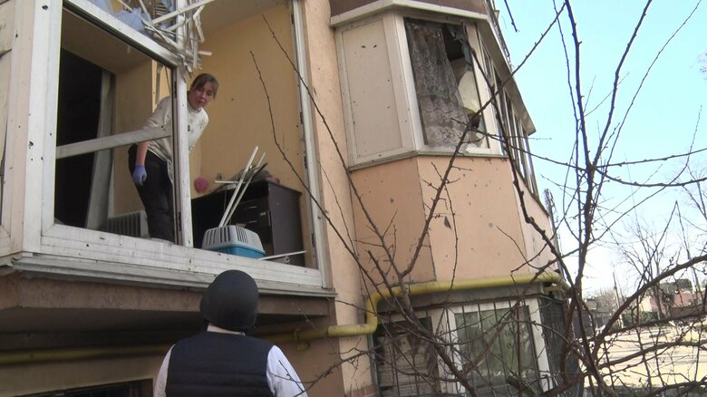 壁が崩れ落ちた自宅を片付ける女性