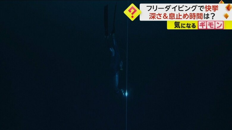 両足のフィンを使い、ゆっくりと潜水していく男性