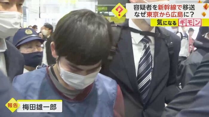 捜査員に囲まれながら歩く男