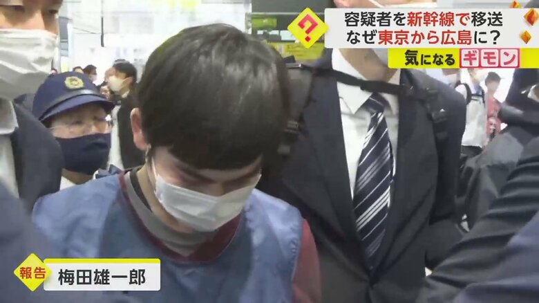 捜査員に囲まれながら歩く男