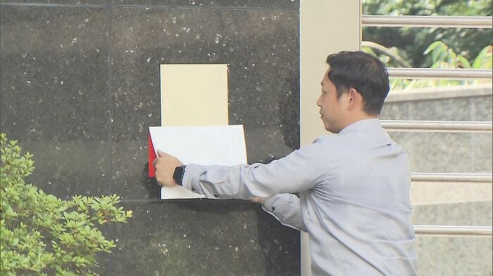 福岡県警の職員によって剥がされる野村被告宅の標章