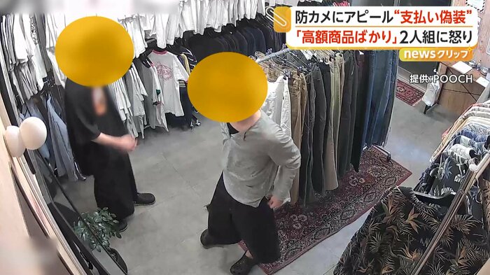 無人古着店で洋服や帽子などを鏡で合わせる2人組