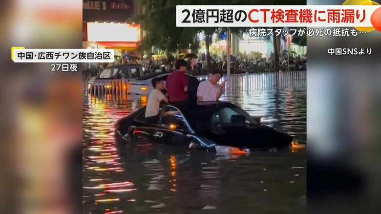 水に浸かった車の屋根にのぼり、途方に暮れる人の姿