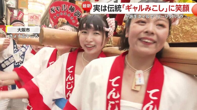 ねじり鉢巻きに、赤と白のはっぴ、みこしを担ぐ多くの女性の姿