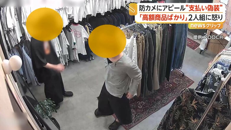 無人古着店で洋服や帽子などを鏡で合わせる2人組