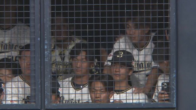 通路の網越しに見つめる選手たち