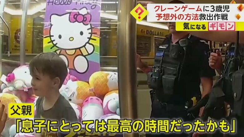 男の子が閉じ込められたクレーンゲームに近づく警察官