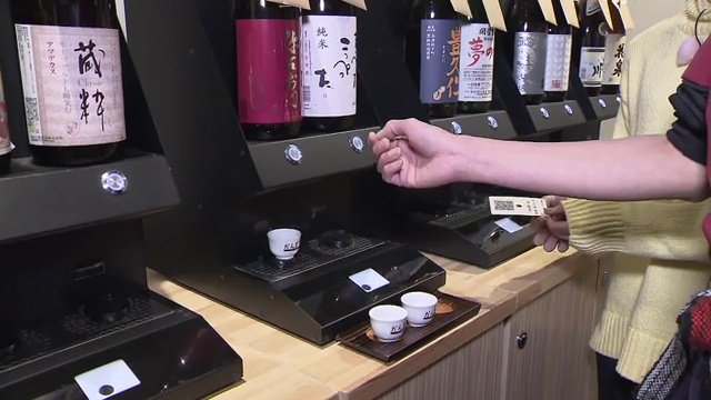 客が飲みたい日本酒のボタンを押して注ぐ