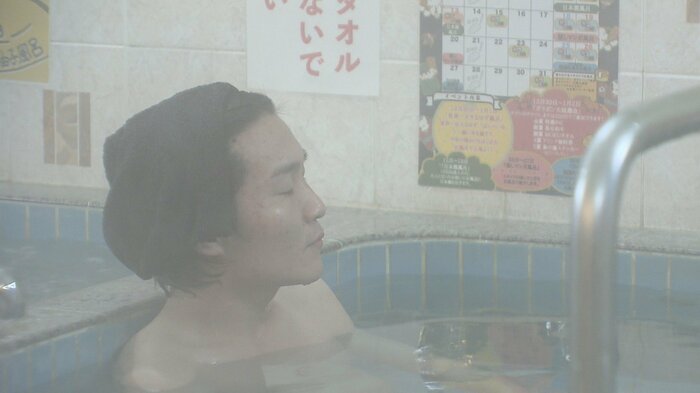 仕事終わりに朝風呂に浸かる男性