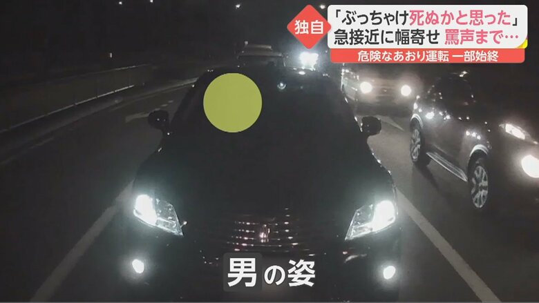 信号待ちする男性の後ろに止まった黒の高級車