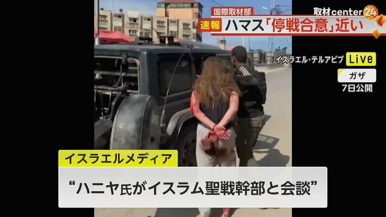 乱暴に引っ張られ、車に乗せられる負傷した人質