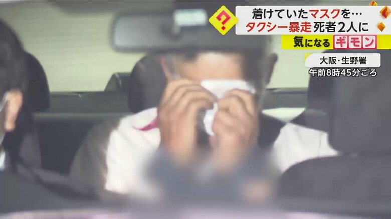 大阪・生野署から出てくるパトカーの中。男はマスクで顔を隠す