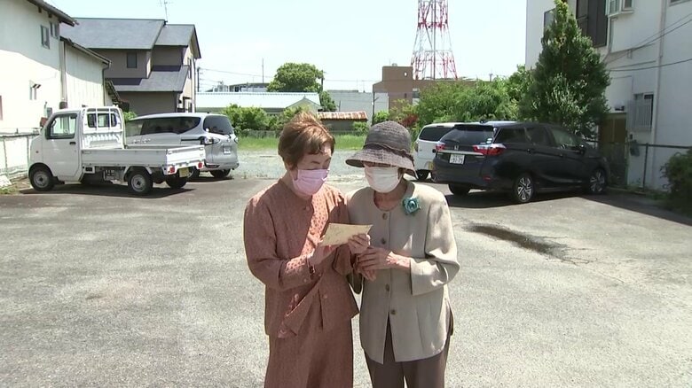 菊池市を訪れ、写真を見つめる丸山さん(左)と中野さん(右)