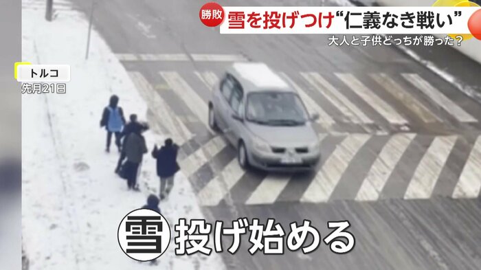 走っていく車に雪を投げる子どもたち(IHA)