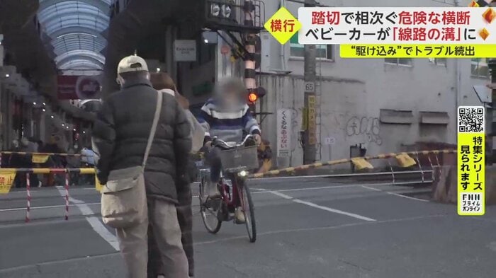 遮断棒を押しのけて通っていく自転車