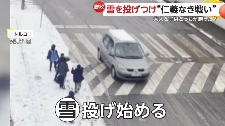 走っていく車に雪を投げる子どもたち（IHA）