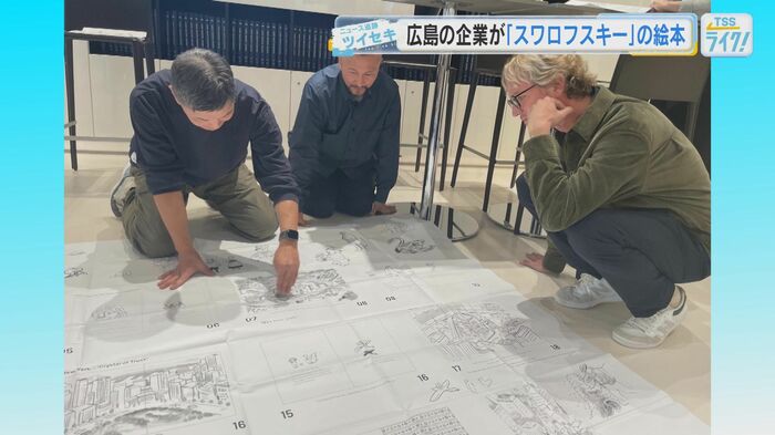 絵本のラフ案を広げ、マーカス氏にプレゼンするカミガキさん