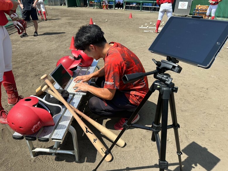 炎天下のグラウンドでデータ分析に勤しむ磯和氏