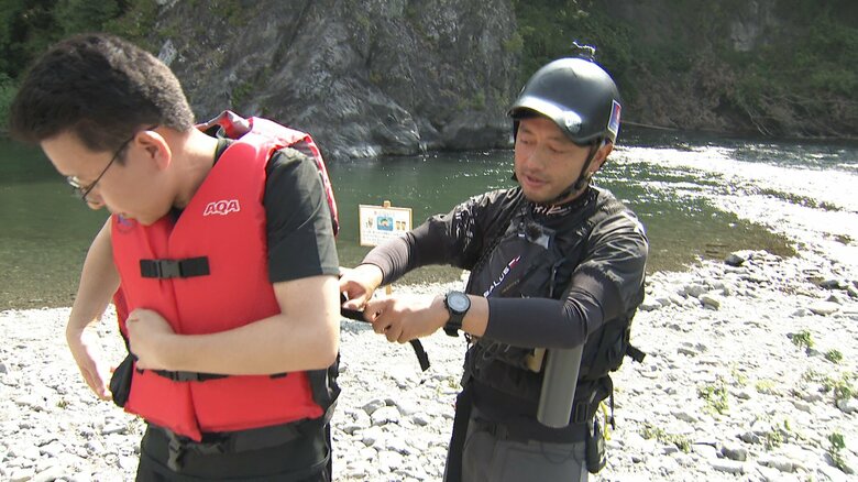 菅原さんからライフジャケット着用の手ほどきを受ける上垣アナ