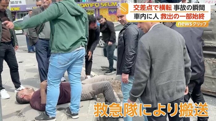 横たわるドライバーと様子をうかがう通行人たち（IHA）