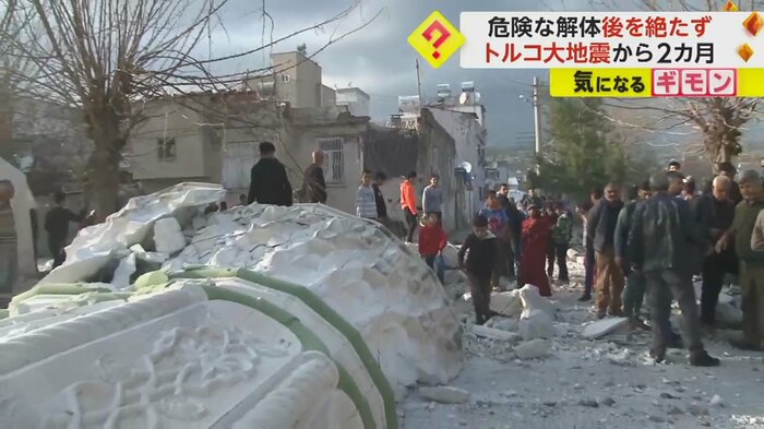 住宅を直撃し倒れている塔。周りにはがれきが散乱し、人が集まっている