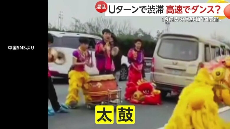 高速道路上で踊る踊り回る中国の獅子舞　すぐそばで太鼓をたたくメンバーも