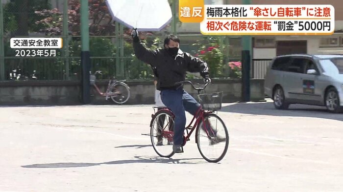 傘さし運転の危険性をスタントマンが実演