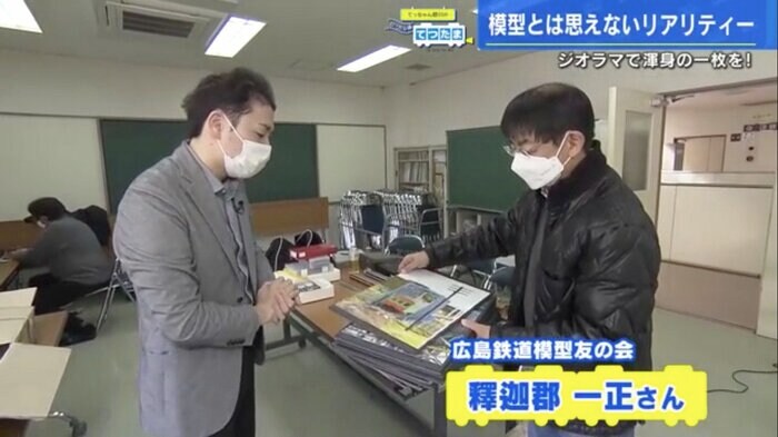 鉄道模型の写真パネルを見せてもらう野川アナ(左)