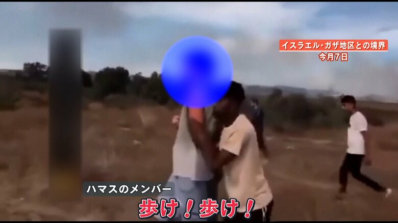 女性が手を伸ばした先には同じく拘束された女性の夫が